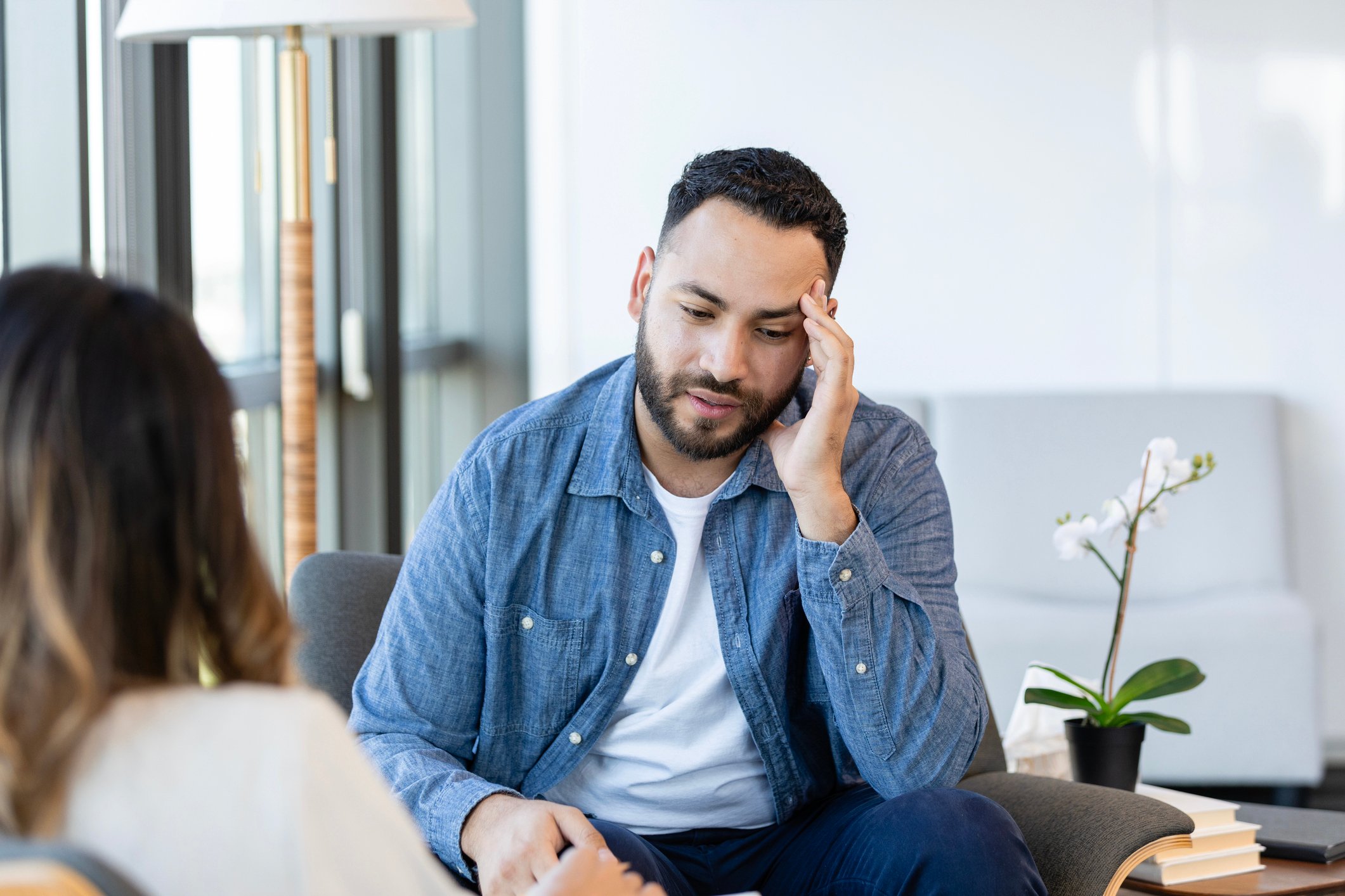 Man in therapy with his head in his hand thinking hard