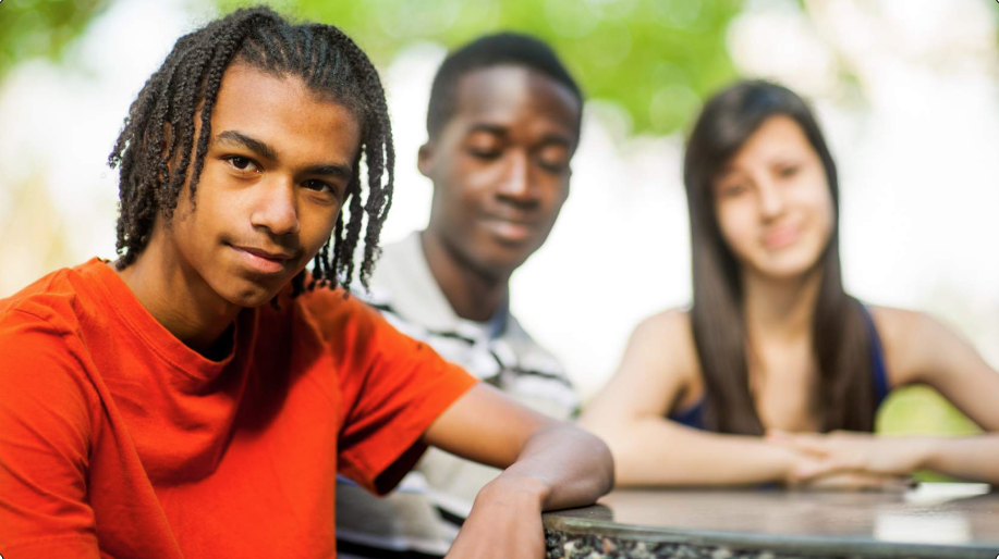 Three teens sitting at an outdoor table