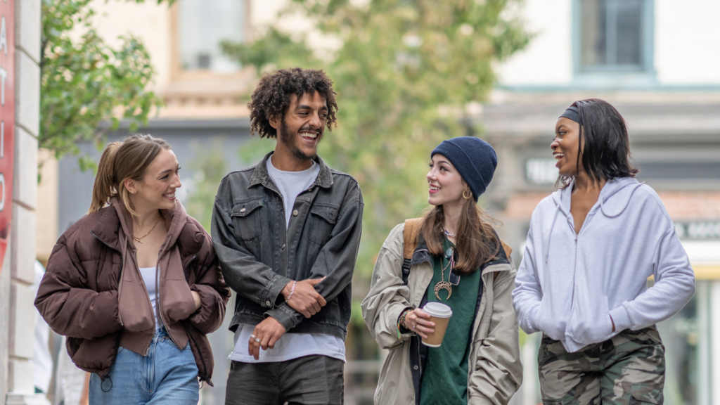 group of 4 teens walking down sidewalk in a town/city