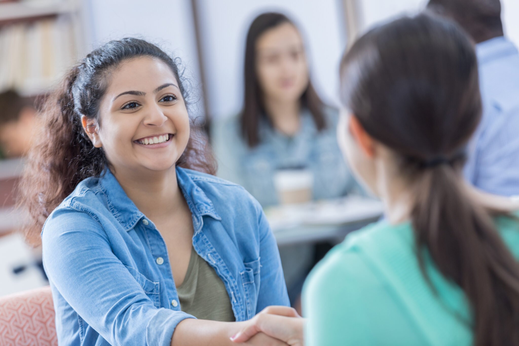 people in a room, chatting with each other, some shaking hands in introduction