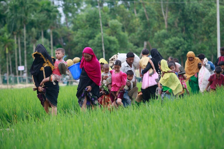 groups of families walking in a line carrying many items with them