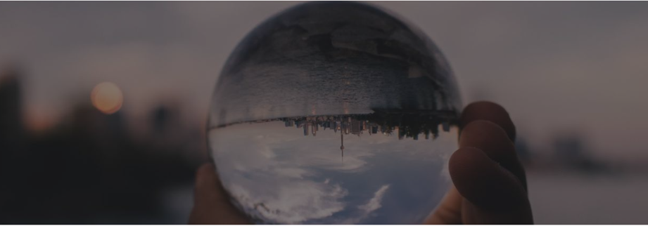 a hand holding a glass sphere that reflects everything upside down