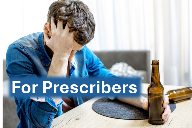 Frustrated man sitting at a table holding his head with one hand and a beer bottle in the other